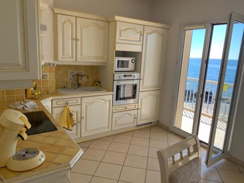 een keuken met witte kasten en uitzicht op de oceaan bij Le Latania in Sainte-Maxime