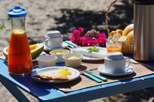 a blue table with a breakfast of eggs and juice at Vila Prana in Barra Grande
