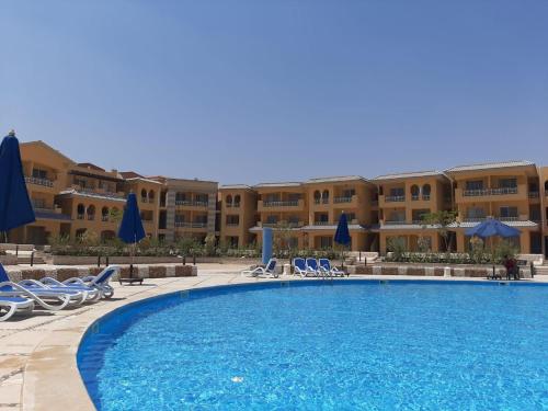a swimming pool with chairs and umbrellas in a resort at بورتو السخنه الكاربيان العاب مائيه - عائلات فقط in Ain Sokhna