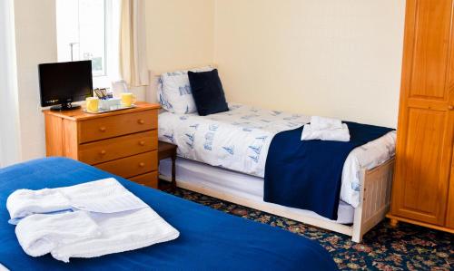 a bedroom with two beds and a dresser with a tv at Braemar in Shanklin