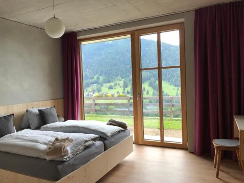 ein Schlafzimmer mit einem Bett und einem großen Fenster in der Unterkunft Kieferhof in Iselsberg