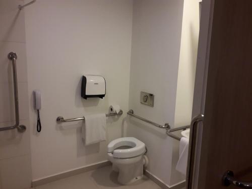 a bathroom with a toilet and a phone on the wall at ibis budget Osasco in Osasco