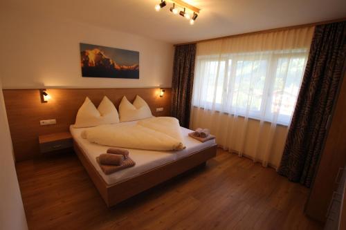 Schlafzimmer mit einem Bett mit weißer Bettwäsche und einem Fenster in der Unterkunft Haus Waldeck - Appartement Bergwelten in Hippach