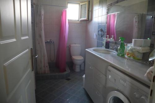 baño con lavabo, aseo y cortina de ducha rosa en MYRTO VIVARI, en Vivari