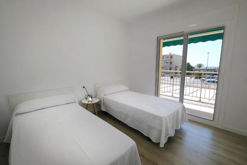 two beds in a room with a large window at Apartaments Àlex in Cambrils