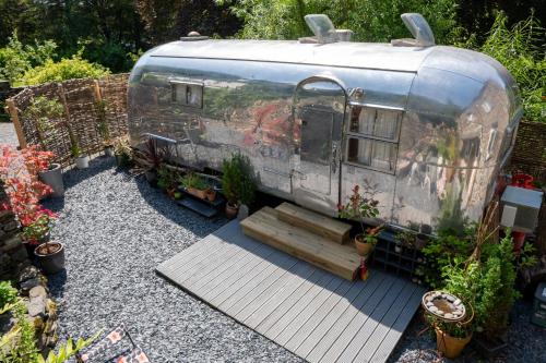 un vieux wagon garé dans une cour avec des plantes dans l'établissement Dixie Airstream - Retro 1970s American Airstream close to Windermere, à Staveley
