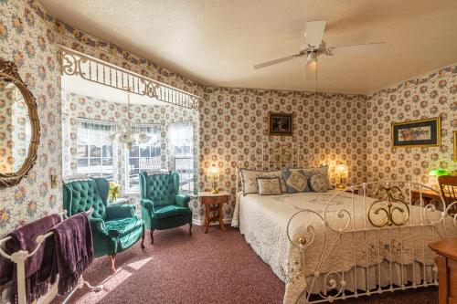 a bedroom with a bed and two green chairs at Apples Bed and Breakfast Inn in Big Bear Lake