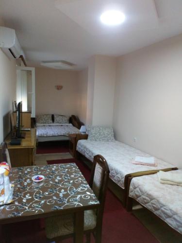 Cette chambre comprend 3 lits et une table. dans l'établissement Guest House Green view, à Pirot