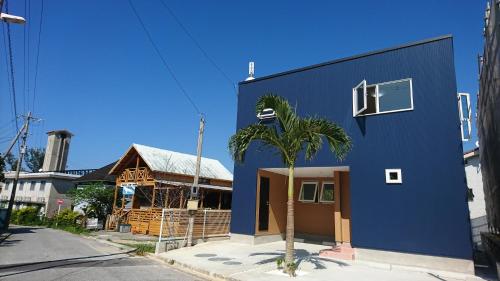 a blue building with a palm tree in front of it at Comfort Villa V "limited to one group" in Inbu