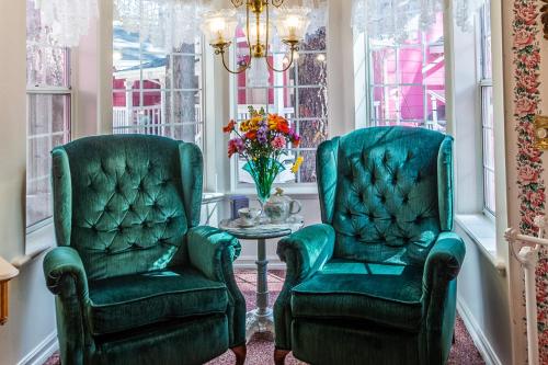 two green chairs and a table in a room with windows at Apples Bed and Breakfast Inn in Big Bear Lake