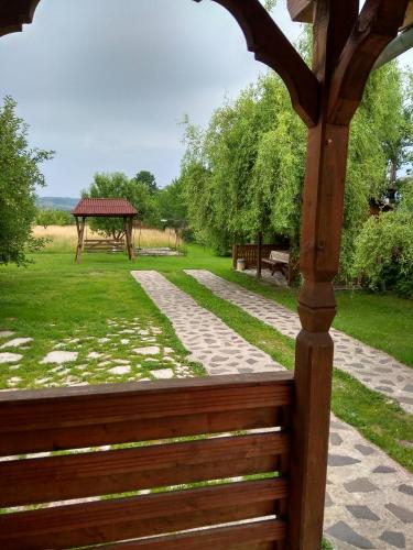 a wooden gazebo with a bench in a park at Casa Adriana in Săpînţa
