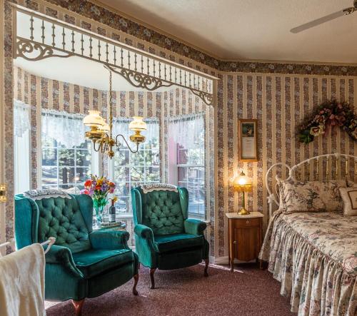 a bedroom with two chairs and a bed and a window at Apples Bed and Breakfast Inn in Big Bear Lake