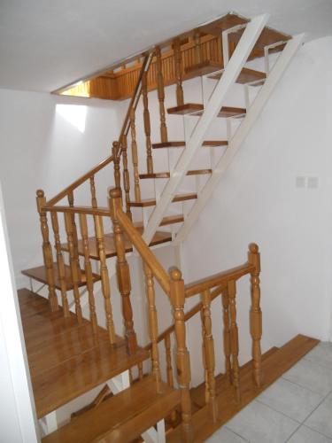 a wooden spiral staircase in a white room at Beta Apartman in Bük