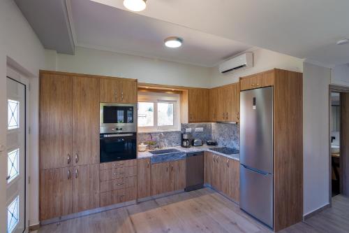 a kitchen with wooden cabinets and a stainless steel refrigerator at Bitsakis Family II - Paleochora Luxury House in Palaiochóra