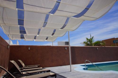 a patio with chairs and an umbrella next to a pool at Hotel Zar La Paz in La Paz