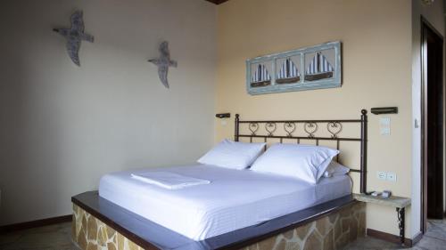 1 cama con sábanas blancas y almohadas en una habitación en Margina Residence Hotel, en Gáios