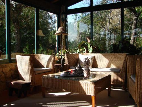 a screened in porch with wicker chairs and a table at Quinta Verde Sintra - Casa de Campo in Sintra