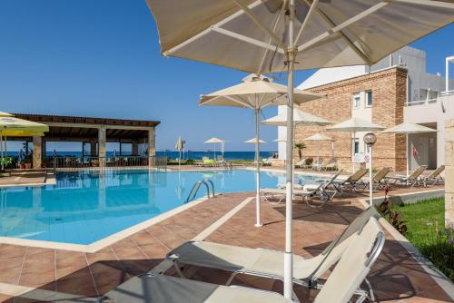 a swimming pool with chairs and umbrellas at Kostakis Beach in Gerani Chanion