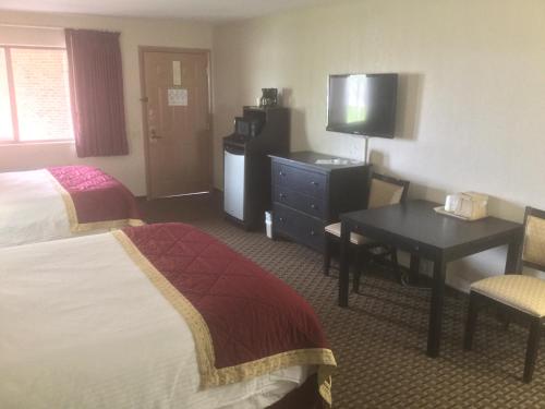 a hotel room with two beds and a desk and a television at Baymont by Wyndham Cortez in Cortez