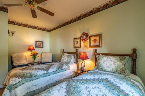 a bedroom with two beds and two chairs at Apples Bed and Breakfast Inn in Big Bear Lake
