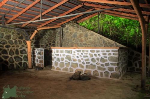 a room with a stone wall and a wooden roof at LUSHOTO EXECUTIVE LODGE in Lushoto