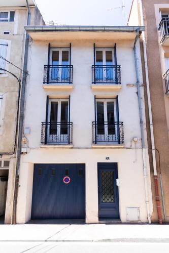 a white building with a black gate and two balconies at Maison La Majorelle - 90m2 - Garage et Terrasse in Pamiers