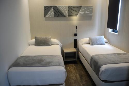 Cette petite chambre comprend 2 lits et une télévision. dans l'établissement Hostal Sevilla Santa Justa - Adults only, à Séville