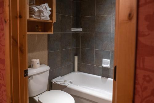 a bathroom with a toilet, sink and tub at Fox Hotel and Suites in Banff