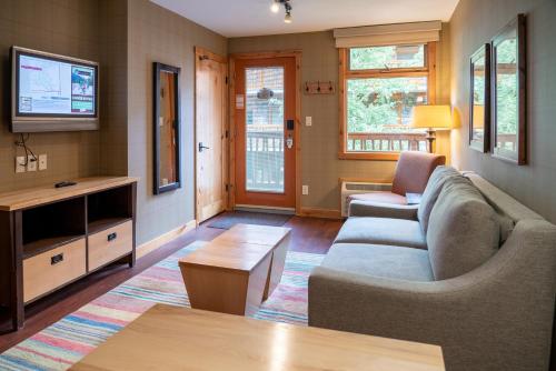 a living room with a couch and a tv at Fox Hotel and Suites in Banff