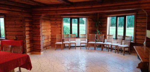 uma sala de jantar com cadeiras e janelas num chalé de madeira em Lielkaibeni em Vecpiebalga