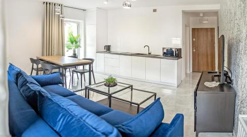 a living room with a blue couch and a kitchen at Corso No 7 APARTMENT in Szczawno-Zdrój