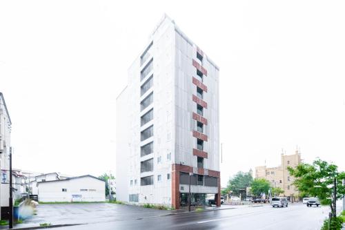 a tall white building on the side of a street at Tabist Annex Hotel Tetora Hakodate in Hakodate