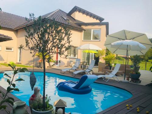 Charming Villa with Private Swimmingpool في Attalens: مسبح وكرسي ازرق ومظله