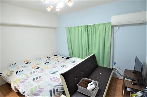 a bedroom with a bed and a television and green curtains at Comfort CUBE PHOENIX MIYAZAKI in Miyazaki