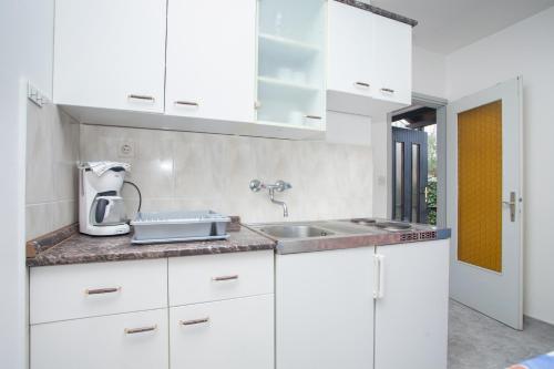 una cocina con armarios blancos y fregadero en Apartments Prenc Pisuko, en Rovinj