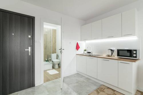 a white kitchen with a sink and a microwave at Andersena 190 A - 12 piętro - 10 min CMKP - 5 min Metro - 15 min Centrum in Warsaw