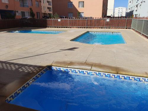 two small swimming pools with blue tiles on a patio at Departamento Amueblado in Antofagasta