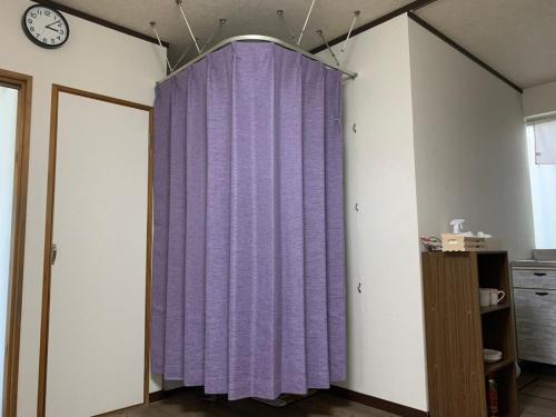 a purple curtain in a room with a clock at ゲストハウス駅近 Gesthouse Ekichika in Naruto in Naruto