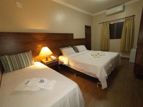una habitación de hotel con 2 camas y una lámpara en Hotel Albatroz, en Uberaba