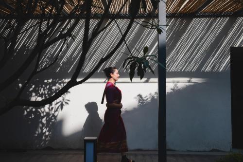 a man walking in front of a wall with a shadow at Percent Hotel Yangshuo in Yangshuo