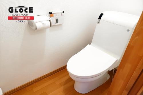 a white toilet in a bathroom with a toilet paper dispenser at GLOCE 美幌 ゲストルーム l BIHORO Guest room in Bihoro