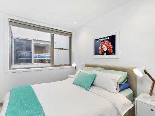 1 dormitorio con cama blanca y ventana en Waterfront Two en Lorne