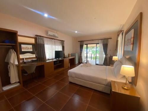 a bedroom with a bed and a desk with a computer at Chaithalay Khanom Resort in Ban Phang Phrao