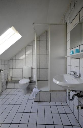 a white bathroom with a toilet and a sink at Hotel Kaufmann in Rommerskirchen