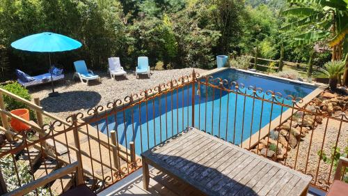- une piscine avec 2 chaises et un parasol bleu dans l'établissement Domaine de la Queyrie, à Sarlat-la-Canéda