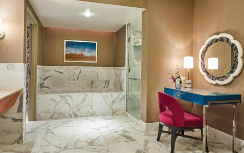 a bathroom with a shower and a desk and a red chair at Borgata Hotel Casino & Spa in Atlantic City