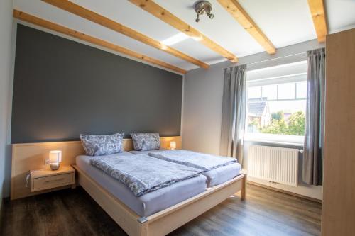 ein Schlafzimmer mit einem Bett und einem großen Fenster in der Unterkunft Apartmenthaus Djuren in Dornum