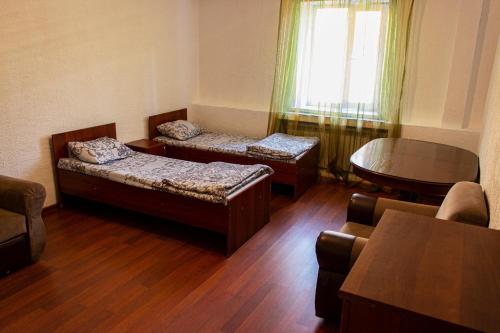 a living room with two beds and a table and a window at Nuri Hotel Стадион in Karagandy