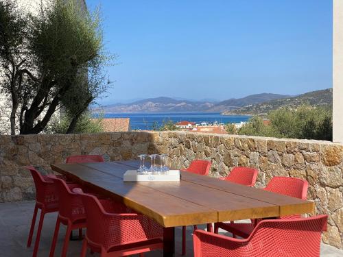 a wooden table with red chairs and a stone wall at Casa u fornu Residence & Spa in LʼÎle-Rousse