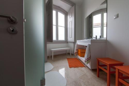 uma casa de banho com um lavatório e uma mesa e algumas janelas em Inn Possible Lisbon Hostel em Lisboa